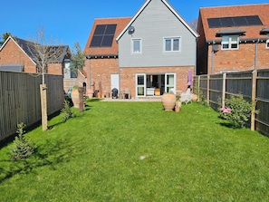 En boligejendom med en velplejet græsplæne, en terrasse med udendørs møbler, og et murhus med solpaneler.
