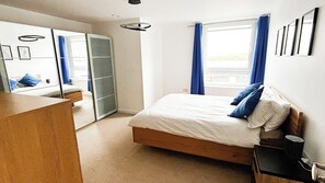 A bedroom with a bed, a wardrobe, a desk, and a window with curtains. - Wonderful 2-bedroom penthouse apartment in peaceful Southampton near local spots (Southampton)