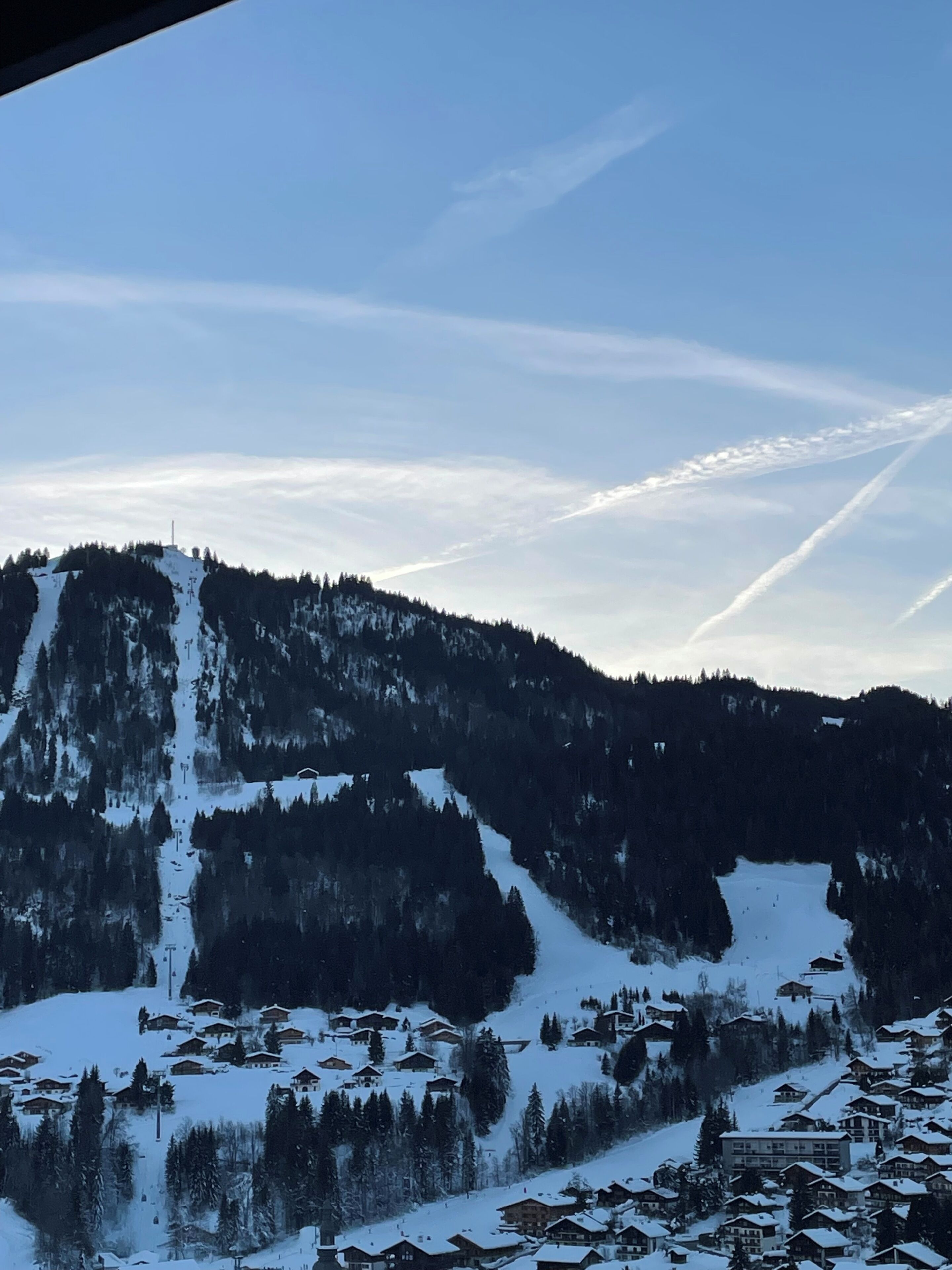 A snow-covered mountain with a ski resort and cabins.