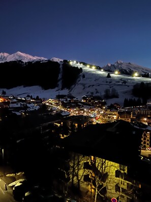 A nighttime view of a snow-covered mountain with a town below, featuring illuminated buildings and a ski slope. - Beautiful Flat Facing La Clusaz Slopes (La Clusaz)