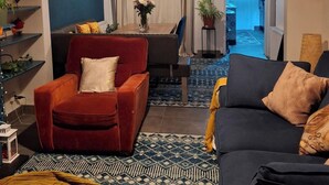 A living room with a red armchair, a black sofa, a patterned rug, and a hanging light fixture. - House Sleeps 6 With Wifi (Belfast)