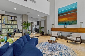 A modern lobby with a blue sofa, a patterned rug, and a large abstract painting. - Spacious Signature 3BR Villa for Golf & Family (Miami)