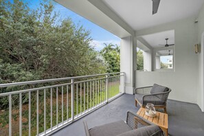 A balcony with a white railing, two wicker chairs, a small table, and a ceiling fan. - Spacious Signature 3BR Villa for Golf & Family (Miami)