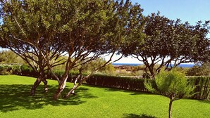 A well-maintained grassy area with mature trees and a distant view of a coastal landscape. - Apartment 'Angolo di Paradiso - Pavoncelle' with Sea View, Private Terrace & Air Conditioning (Orosei)
