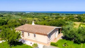 A single-story house with a tiled roof, surrounded by greenery and a view of the sea. - Apartment 'Angolo di Paradiso - Pavoncelle' with Sea View, Private Terrace & Air Conditioning (Orosei)