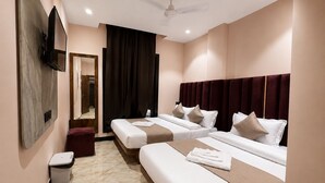 Habitación de hotel con dos camas, un televisor, un espejo, un cesto de basura y un ventilador de techo.