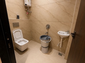 A compact bathroom with a toilet, bidet, and sink. - Hotel Old City Inn (Ujjain)