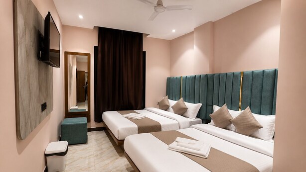 Una habitación de hotel con dos camas, televisión, ventilador de techo y baño.