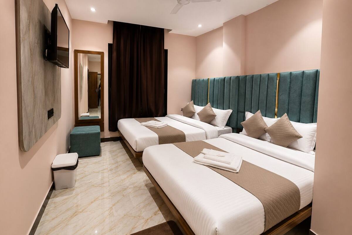 A hotel room with two beds, a TV, a ceiling fan, and a bathroom.