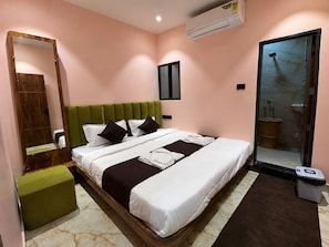 A hotel room with a bed, a green upholstered bench, a mirror, an air conditioning unit, and a bathroom with a marble floor. - Hotel Old City Inn (Ujjain)