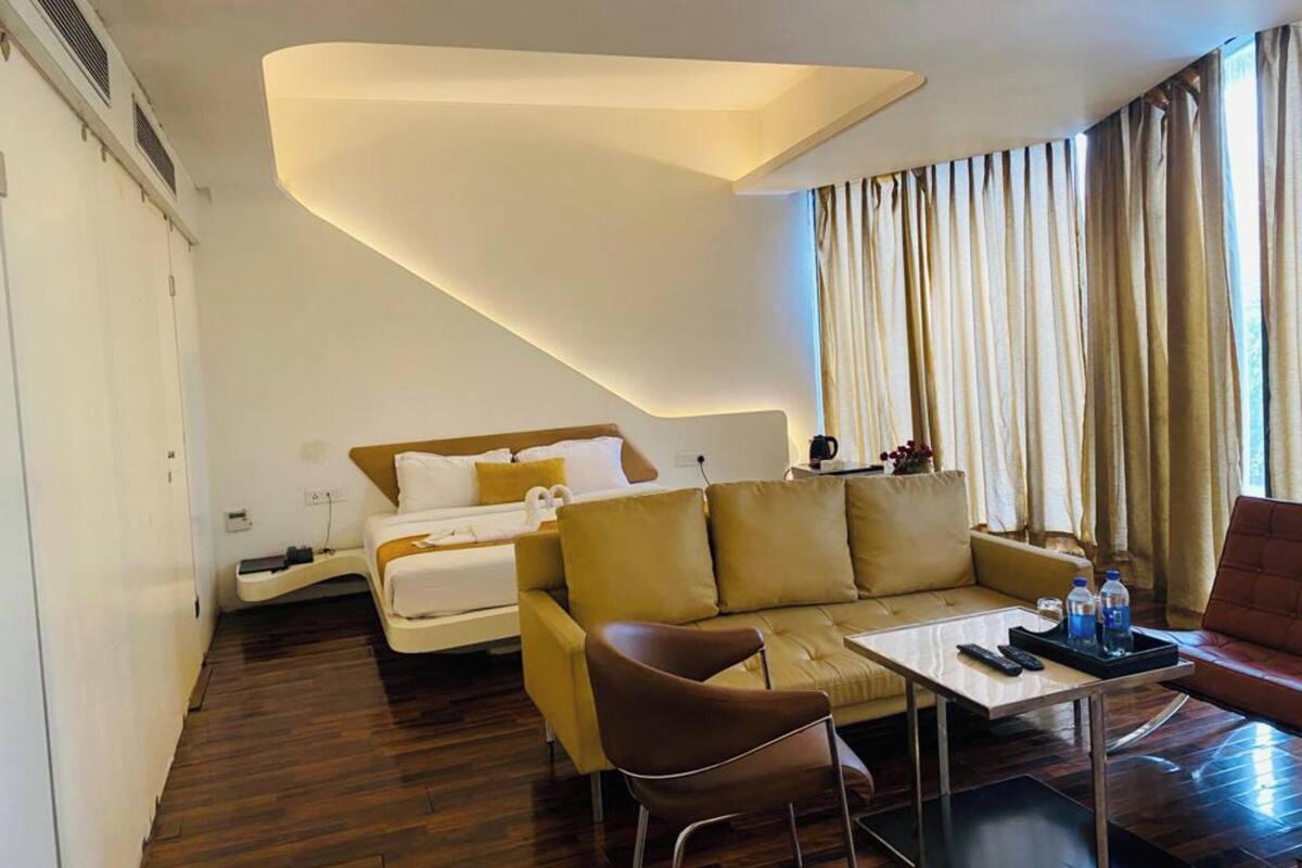Ein modernes Hotelzimmer mit Bett, einer Couch, einem Esstisch und einem Stuhl.