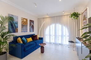 Un salon moderne avec un canapé bleu, une table basse et des œuvres d’art accrochées au mur.