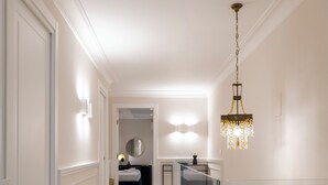 Ein Flur mit einer Zimmerpflanze, einem Chandelier und einem Bett im Hintergrund.