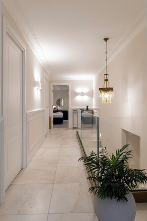 Ein Flur mit einer Zimmerpflanze, einem Chandelier und einem Bett im Hintergrund.
