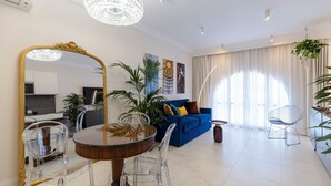 Ein modernes Wohnzimmer mit Essbereich, einem blauen Sofa und einer Chandelier.