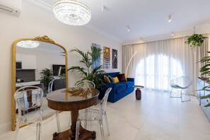 Ein modernes Wohnzimmer mit Essbereich, einem blauen Sofa und einer Chandelier.