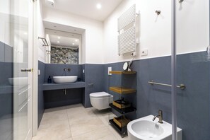Une salle de bain moderne avec une douche à parois de verre, un lavabo blanc, des toilettes et un meuble-lavabo avec un miroir.