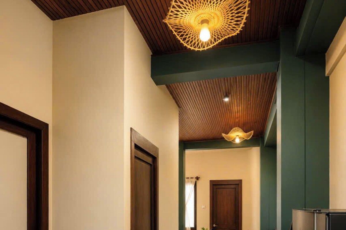 Um corredor com ladrilhos estampados, teto de madeira e luminária moderna.