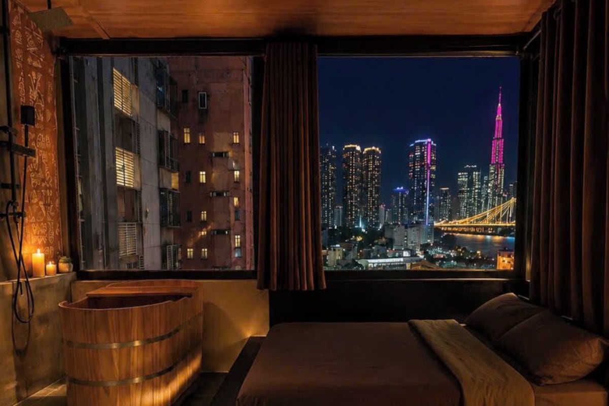 A modern bedroom with a city view, a wooden bathtub, and a patterned floor.