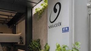 A modern building entrance with a concrete wall, a large logo, and potted plants.