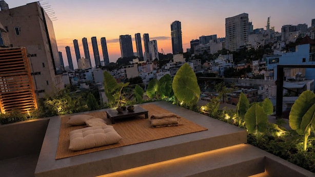 A rooftop terrace with a seating area, steps, and a cityscape view at dusk.