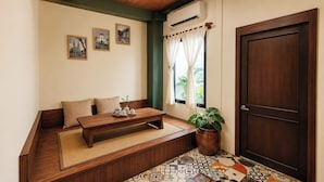 A room with a wooden bench, a small table with teapots, a potted plant, and a door.