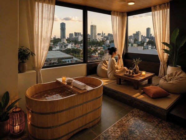 Habitación con una bañera de madera, un sofá, una mesa con juego de té y vistas a la ciudad.