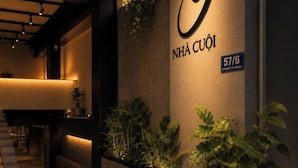 A modern interior with a prominent illuminated logo, a staircase, and planters with greenery.