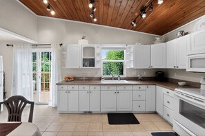 A kitchen with white cabinets, a black countertop, and a window with a view of greenery. - Family-Friendly Aloha Home Near Intel & Nike (Aloha)