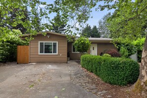 A single-story house with a front porch, a wooden fence, and a well-maintained hedge. - Family-Friendly Aloha Home Near Intel & Nike (Aloha)