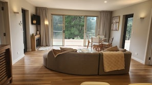 A modern living room with a sectional sofa, a dining table with chairs, and a fireplace.