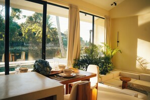 Un salon moderne avec un coin repas, de grandes fenêtres et une vue sur la verdure environnante.