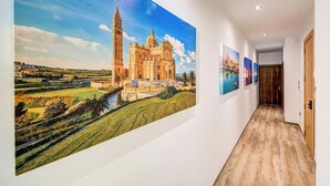 A hallway with a large mural of a historic building, a wooden floor, and a door on the right. - 2BR Maisonette Near St. Paul`s Bay & Beaches (St. Paul`s Bay)