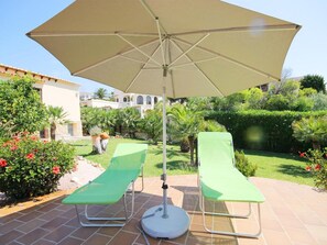 An outdoor seating area with two green lounge chairs and a large beige umbrella. - Villa- Calypso in J vea (Javea)