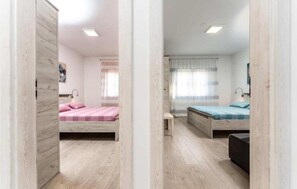 Una camera da letto con due letti, una panca e un piccolo tavolo.