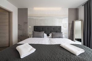 Ein ordentlich bezogenes Bett mit einer dunklen Decke, zwei Kissen und zwei gefalteten weißen Handtüchern.