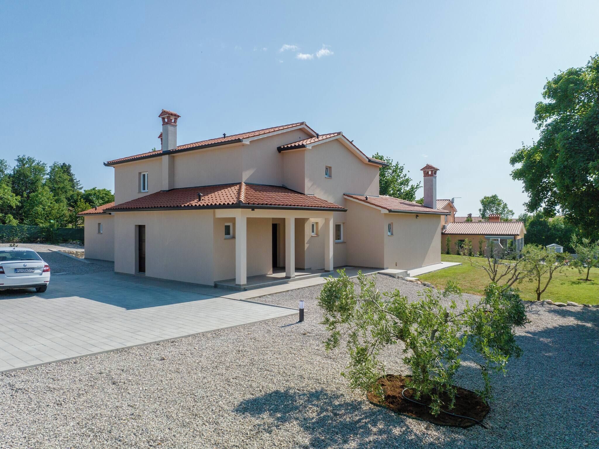 Une maison à deux étages, avec un toit en tuiles, une allée et un petit jardin.