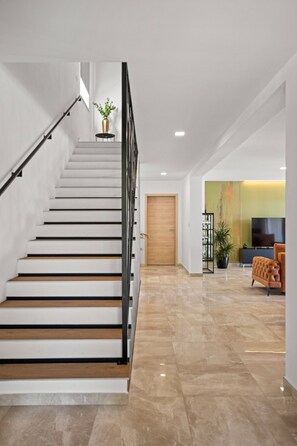 Eine moderne Treppe mit Holzausstattung, einem schwarzen Geländer und einem Blumentopf oben.
