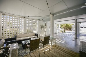A covered outdoor seating area with a white lattice partition, a sofa, wicker chairs, and a glass table. - 2BD, 2BA duplex just 470 ft from beach access at Wrightsville Beach! (Wrightsville Beach)