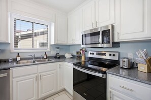 A modern kitchen with white cabinets, a double oven, a microwave, and a toaster. - This apartment is a 2 bedroom(s), 2 bathrooms, located in Wrightsville Beach, NC. (Wrightsville Beach)