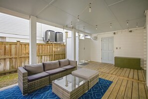An outdoor patio with a wicker sofa, a glass-top coffee table, and a wooden deck. - This apartment is a 2 bedroom(s), 2 bathrooms, located in Wrightsville Beach, NC. (Wrightsville Beach)