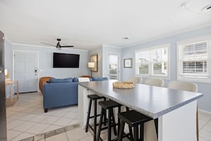 A modern kitchen with a central island, bar stools, and a dining area with chairs. - This apartment is a 2 bedroom(s), 2 bathrooms, located in Wrightsville Beach, NC. (Wrightsville Beach)