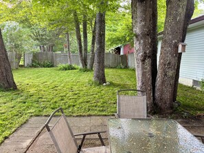 Ein Garten mit Tisch und Stühlen, einem Holzzaun und Bäumen.