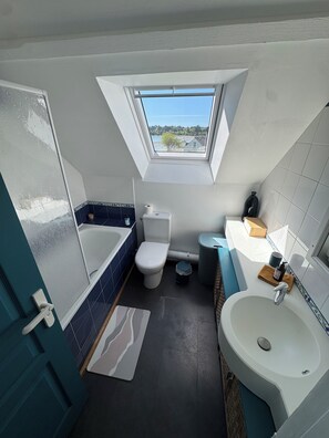 Un baño moderno con tragaluz, bañera, inodoro y lavabo.
