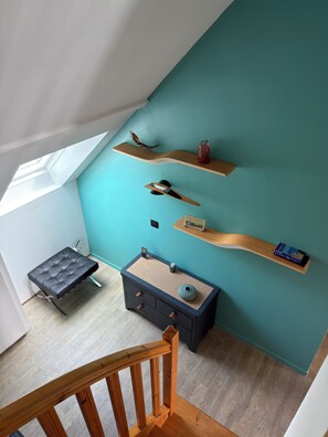 A room with teal walls, a wooden bench, a small table, and multiple shelves with various items. - Apartment with terrace, sea view, direct beach access. Fiber. Refurbished. GR34. (Fouesnant)