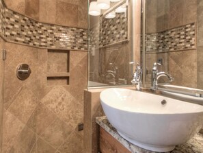 Une salle de bain avec un lavabo blanc, un miroir et un espace douche.