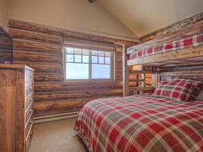 A cabin-style bedroom with a bunk bed, a dresser, and a window with a view. - New to VRBO - Cowboy Heaven Cabin, Yellowstone Country, Hot Tub, Amazing Views! (Big Sky)