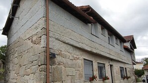 Un bâtiment en pierre doté d’un toit en pente, de nombreuses fenêtres et d’une cheminée bien visible.