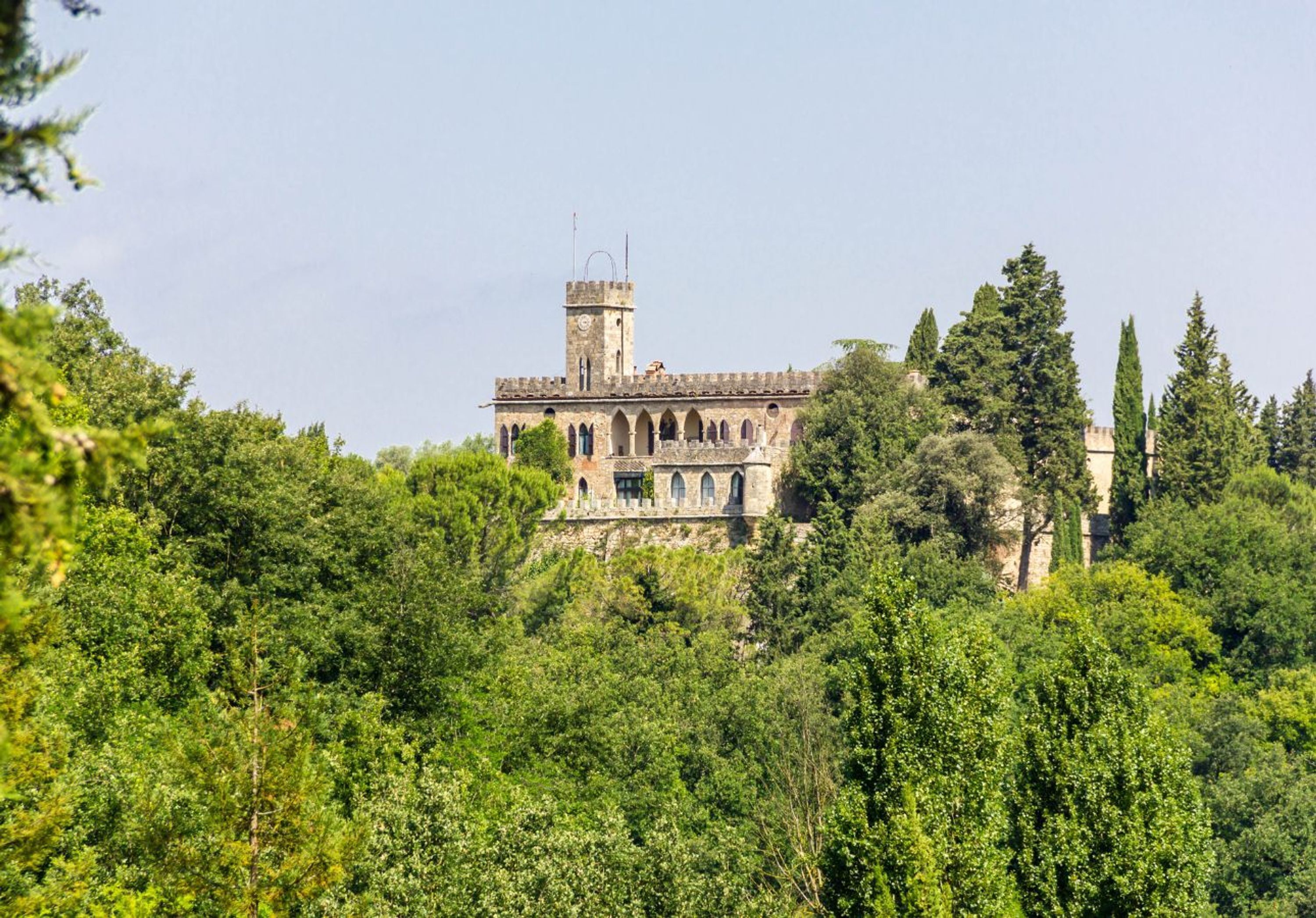 A historic building with a tower, surrounded by dense greenery.