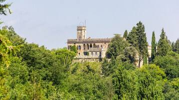 A historic building with a tower, surrounded by dense greenery.